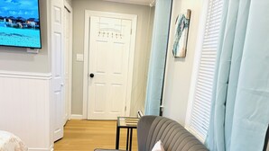 A living room with a grey sofa, a patterned rug, and a television mounted on the wall. - 1-bedroom unit with Private Entrance/ Laundry/Kitchen/Parking (Abington)