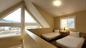 Un dormitorio con dos camas, una mesita de noche, una lámpara y una ventana con persianas.