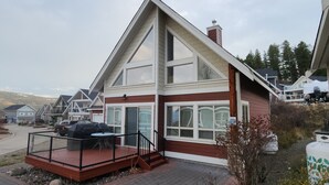 Una casa moderna de dos pisos con un balcón grande y un espacio techado para sentarse al aire libre.