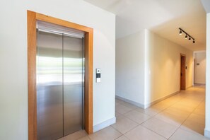 A hallway with a modern elevator and a door leading to another room.