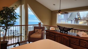 Ein Balkon mit Blick auf ein Gewässer, ein Stuhl, ein Tisch und ein Deckenventilator.