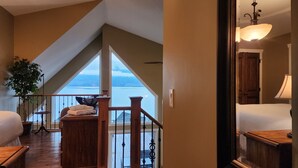 Ein Zimmer mit Blick auf ein Gewässer, einer Holzbank, einer Pflanze und einer Lampe.