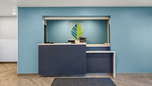 Un mostrador de recepción con una pared azul, un logotipo en la pared y una alfombra gris.