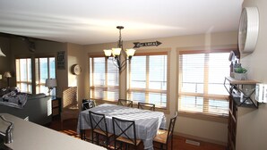 A dining area with a table set for four, a chandelier, and a 'Eat Local' sign. - Beautiful 3 Bedroom Pet Friendly Cottage on Lake Okanagan (West Kelowna)