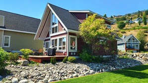 A modern two-story house with a prominent gable roof, large windows, and a stone foundation. - Gorgeous Lakeview 2 Bedroom  and  Loft Cottage on Lake Okanagan (Kelowna)