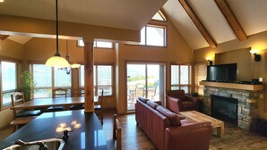A spacious living area with a fireplace, a dining area with a large table, and a seating area with a sofa. - Gorgeous Lakeview 2 Bedroom  and  Loft Cottage on Lake Okanagan (Kelowna)