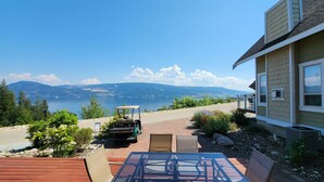 A patio with a table and chairs, a golf cart, and a view of a lake and mountains. - Gorgeous Lakeview 2 Bedroom  and  Loft Cottage on Lake Okanagan (Kelowna)