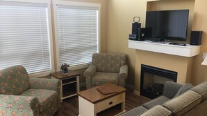 A living room with a sofa set, a coffee table, a fireplace, and a TV on a stand.