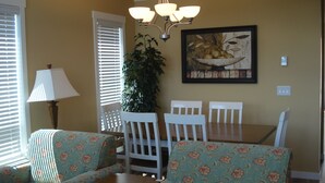 A dining area with a table and chairs, a lamp, and a painting on the wall.