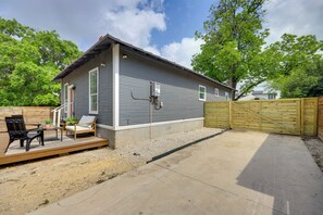 Ein Bungalow mit überdachter Terrasse, Holzdeck und einem eingezäunten Garten.