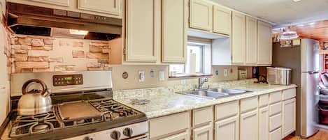 Enjoy cooking in this well-equipped kitchen with a central stove, oven, and sink, plus a microwave and refrigerator.