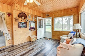 Cozy cabin interior with a wooden-paneled ceiling and large window offering a serene view of the surrounding landscape.