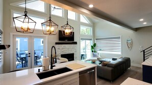 A modern kitchen with a large island, pendant lights, and a view to the outside. - Stunning Modern Cottage at La Casa Lakeside Resort (Kelowna)