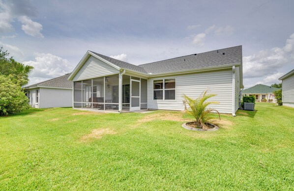 A single-story house with a covered porch, a small front yard, and a palm tree.