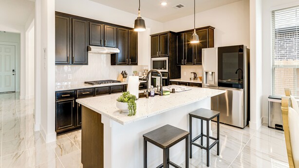 A modern kitchen with dark cabinetry, a central island with stools, stainless appliances, and pendant lighting. - Patio & Pool Access: Family Home in Tomball (Hockley)