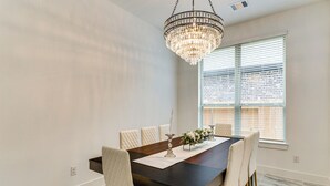 A dining area with a dark wooden table, six upholstered chairs, a chandelier, and a window with blinds. - Patio & Pool Access: Family Home in Tomball (Hockley)