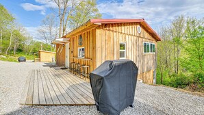A wooden cabin with a deck, a covered grill, and a bar area with stools. - Secluded on 10 Acres: Livingston Getaway w/ Sauna! (Livingston)