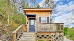 A wooden cabin with a front door, a small porch with a railing, and a staircase leading up to the entrance. - Secluded on 10 Acres: Livingston Getaway w/ Sauna! (Livingston)