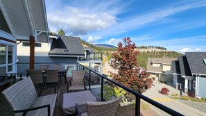 A balcony with wicker furniture and a view of a residential area with houses and trees. - Charming 2 Bed  and  Loft Cottage at La Casa Lakeside Resort (Kelowna)