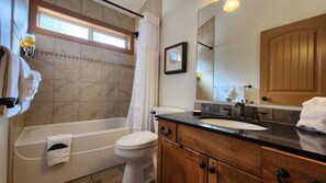 A bathroom with a bathtub, toilet, sink, vanity, and a large mirror. - Charming 2 Bed  and  Loft Cottage at La Casa Lakeside Resort (Kelowna)