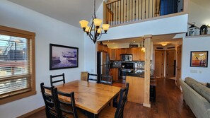 A spacious kitchen with wooden cabinets, a central island, and a dining area with a wooden table and chairs. - Charming 2 Bed  and  Loft Cottage at La Casa Lakeside Resort (Kelowna)