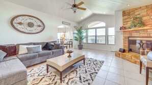 Un salón amplio con un sofá seccional gris, una mesa de centro, una chimenea y un espejo decorativo grande en la pared.