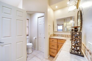 A bathroom with a toilet, wooden cabinets, a sink, and a mirror. - Stunning Mountain Views: Peaceful Payson Retreat! (Payson)