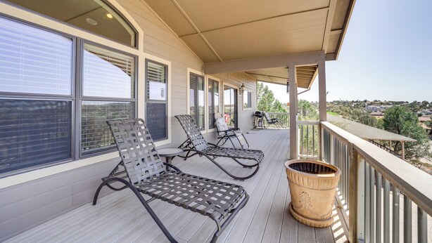Un espacio al aire libre techado con tres tumbonas, una jardinera grande y vistas a un barrio residencial.