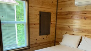 A wooden room with a bed, a window, and an air conditioning unit. - Tiny Homes for Rent, minutes to the Casino, Golf Course & Water Park (Philadelphia)