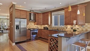 A modern kitchen with wooden cabinets, stainless steel appliances, and a wine rack.