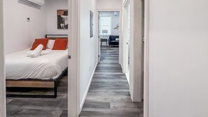 Ein Hotelgang mit einem Bett links, einer Couch in der Mitte und einem Sessel im Hintergrund.