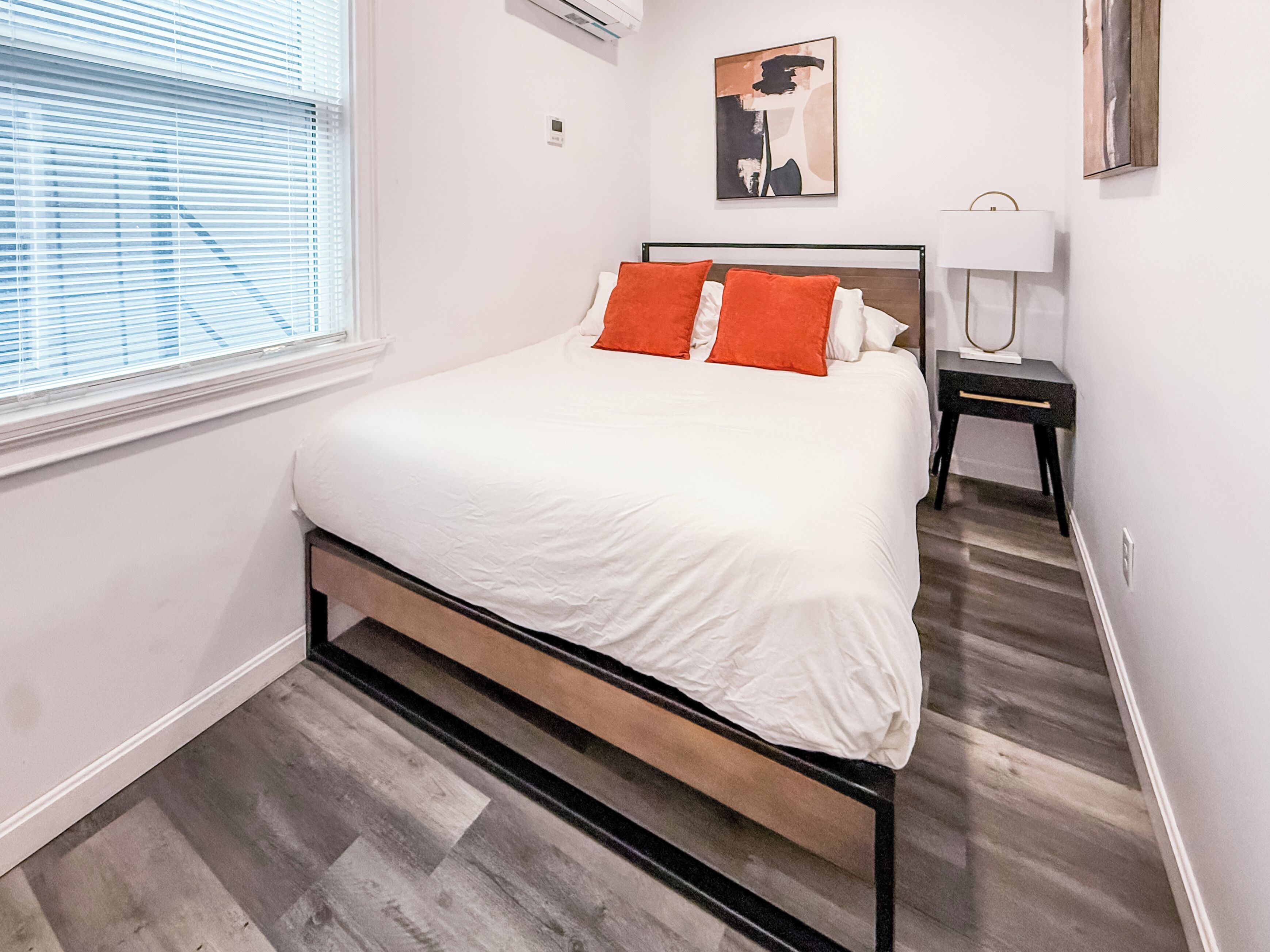 Una camera da letto moderna con un letto, un comodino, una lampada e un quadro appeso al muro.