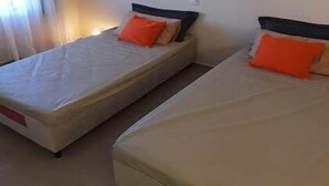 Een kamer met twee eenpersoonsbedden, elk met een matras en kussen.