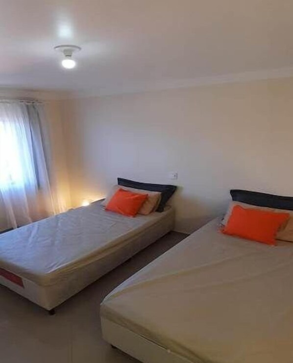 A room with two single beds, each with a mattress and a pillow. - Apto 502 Residencial GM bem localizado (Piratuba)