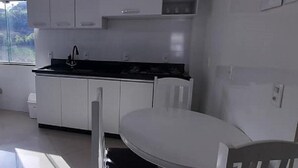 Een moderne keuken met witte kasten, een zwart aanrecht en een eettafel met stoelen.