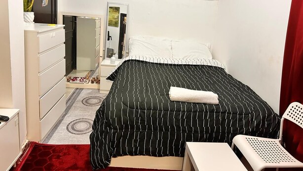 Ein Schlafzimmer mit einem Bett, einem Schminktisch, einem Sessel und einem Spiegel.