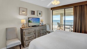 Habitación de hotel con cama, televisor, cómoda y balcón con vista a la playa.