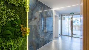 A modern lobby with a green vertical garden, a marble wall, and a glass door leading outside. - Ref. 526211 (Motril)