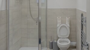 Une salle de bain moderne avec une douche à parois de verre, des toilettes et un sèche-mains.