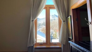 Une pièce avec une fenêtre, des rideaux, une porte et un piano.