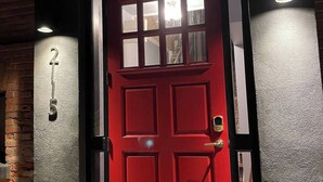 Une porte rouge avec un panneau en verre et le numéro « 25 » sur le mur, à gauche.