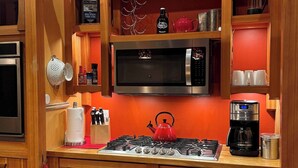 Une cuisine compacte équipée d’une cuisinière à gaz, d’un four à micro-ondes et d’une machine à café.