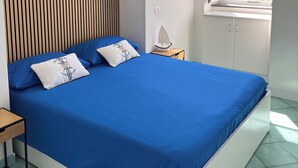 A bedroom with a large bed, a painting on the wall, a window with a view, and a ceiling fan. - SEA BREEZE APARTMENT 2 BATHROOMS 2 ROOMS PRIVATE TERRACE SEA VIEW AIR CONDITIONING (Ponza)