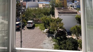 A view from a window overlooking a residential area with buildings, a parked car, and a clear blue sky. - SEA BREEZE APARTMENT 2 BATHROOMS 2 ROOMS PRIVATE TERRACE SEA VIEW AIR CONDITIONING (Ponza)