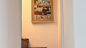 A staircase with wooden steps and a framed artwork depicting a market scene on the wall above. - SEA BREEZE APARTMENT 2 BATHROOMS 2 ROOMS PRIVATE TERRACE SEA VIEW AIR CONDITIONING (Ponza)