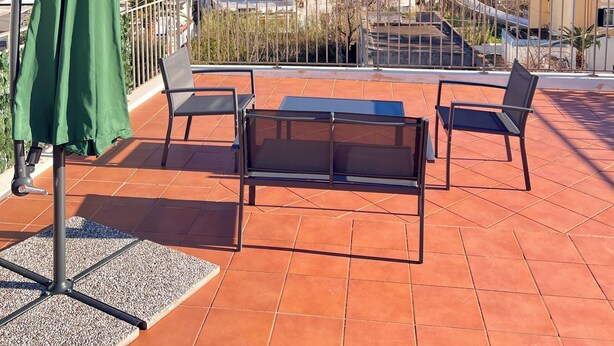 A terrace with a green umbrella, two chairs, and a table. - SEA BREEZE APARTMENT 2 BATHROOMS 2 ROOMS PRIVATE TERRACE SEA VIEW AIR CONDITIONING (Ponza)