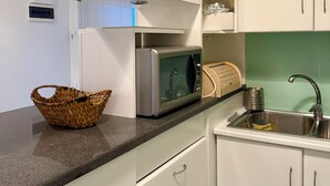 A modern kitchen with white cabinets, a stainless steel sink, a microwave, and a basket on the counter. - SEA BREEZE APARTMENT 2 BATHROOMS 2 ROOMS PRIVATE TERRACE SEA VIEW AIR CONDITIONING (Ponza)