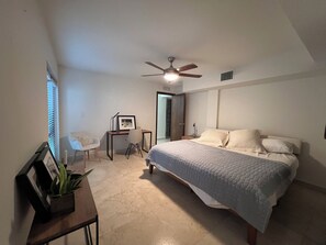 Relax in a serene bedroom with a large bed, ceiling fan, and a small desk for work or reading.