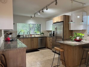 Enjoy cooking in this well-lit kitchen with a sleek island, bar stools, and modern appliances.