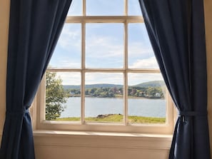 Una ventana con vista a un lago y colinas.